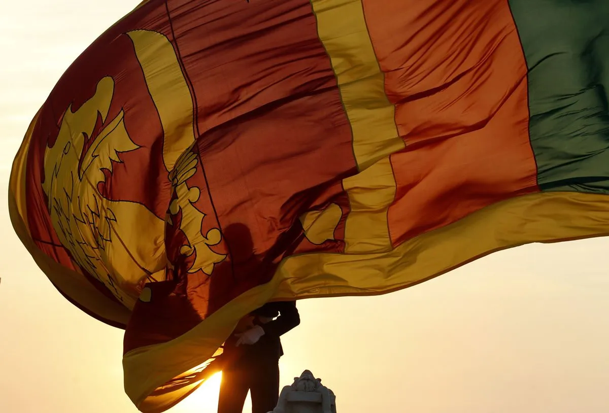 Air force officer holds Sri Lanka’s national flag as the sun sets at Galle Face Green in Colombo